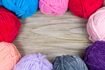 Circled pastel colored yarn on the wooden table blank with blank space in the center.