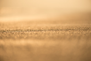 Blur tropical sunset beach with bokeh light sand abstract texture background.