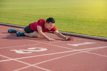 Sad asian runner sitting on the ground after losing in competition
