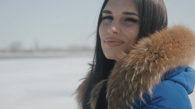 portrait of young beautiful brunette woman in winter on a snow background