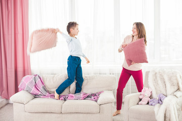 Young mother playing active games with her son. Cheerful family indoors having fun.