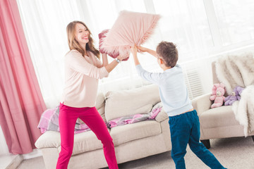 Obraz premium Young mother playing active games with her son. Cheerful family indoors having fun.