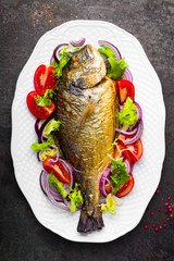 Baked fish dorado. Dorado fish oven baked and fresh vegetable salad on plate. Sea bream or dorada fish grilled and vegetable salad