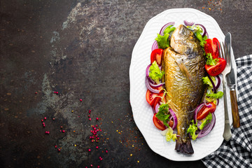 Baked fish dorado. Dorado fish oven baked and fresh vegetable salad on plate. Sea bream or dorada...