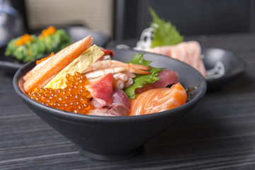 Premium fresh raw seafood mixed rice bowl (Kaisen-don/ Japanese tasty food), Japanese Rice with sashimi of tuna, Maguro, Otoro, salmon, squid and ikura (Salmon eggs) on wood background