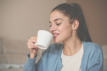 Smiling girl at home drinking  enjoying in coffee.