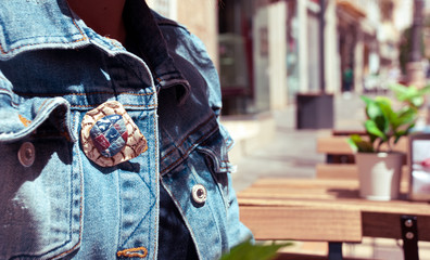 Part of denim woman fashion jacket. Handmade jewelry brooch of polymer clay. Urban background with...
