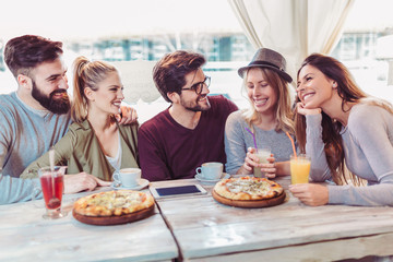 Young friends sharing pizza in a indoor cafe