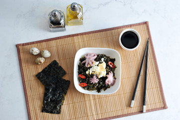salad from sea kaleuropa octopus, eggs and onions - on a background of bamboo napkin - top view