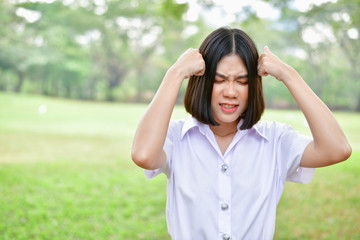 Education Concepts. Beautiful young Asian girl is thinking seriously. Beautiful Asian students are thinking in the garden. Beautiful young student is headache in the garden.