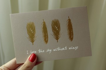 A greeting card with golden feathers saying I love sky without wings