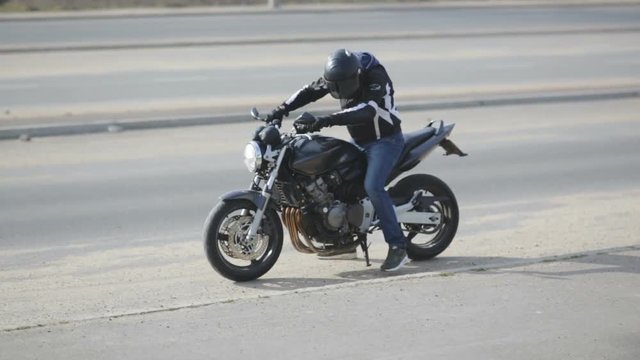 young attractive man motorcyclist with black helmet and sport motorcycle on street 