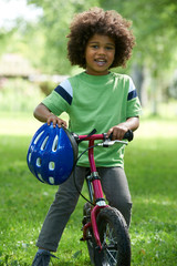 Young Boy Learning To Ride Bike In Park