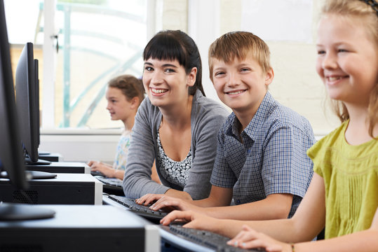 Portrait Of Male Elementary Pupil In Computer Class With Female Teacher
