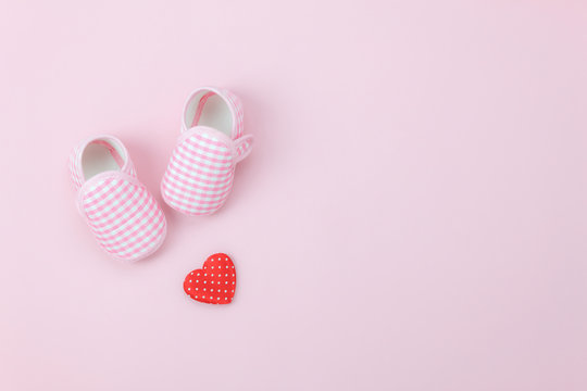 Table top view aerial image of decoration Happy mother’s day holiday background concept.Flat lay red heart & baby shoes on modern beautiful pink paper at home office desk.Design pastel tone and space.