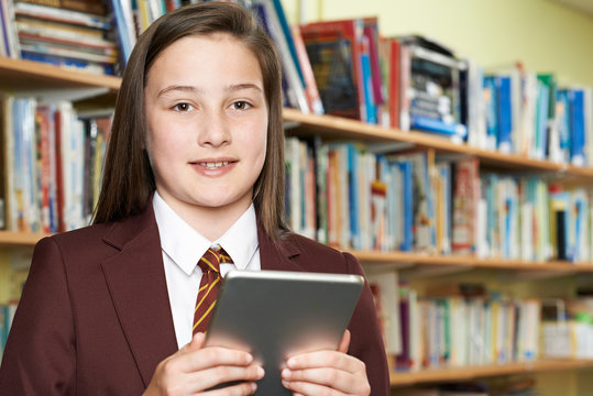 Portrait Of Girl Wearing School Uniform Using Digital Tablet In Library - Powered by Adobe
