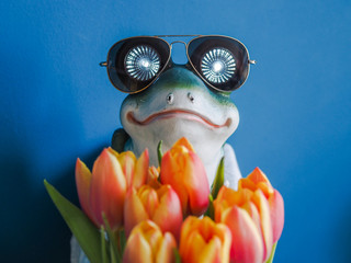 cool frog with sunglasses holding a bunch of flowers and looks like the hidden dream prince