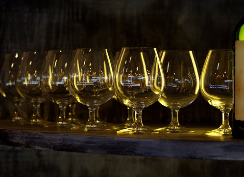 Wine glasses standing in a row near bottle