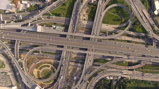 Aerial view of highway road interchange with busy urban traffic speeding on the road, taken by drone. The city highway was taken at eastern Bangkok outer ring road, junction network of transportation.
