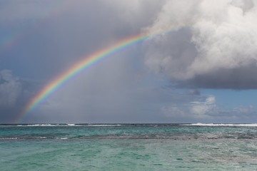 Rainbow, heavy clouds, and rain over a cove in Guadeloupe, Caribbean