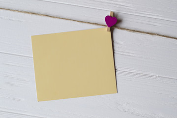 Yellow memo sheet fastened with a decorative pin on a white wooden board.