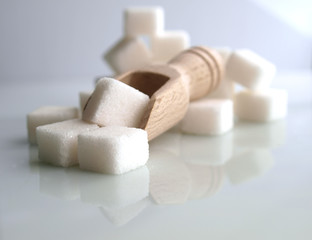 sugar adiction: sugar cubes and wooden spoon over white background.