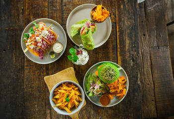 set of vegetarian dishes on a wooden table top view..Pasta, green burger, falafel, shaurma, and lavash from spirulina.