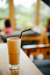 cold cappuccino with cinnamon and a straw on the table in a cafe. Delicious and invigorating drink in the summer cafe.