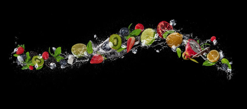 Fototapeta Pieces of fruit in water splash, isolated on black background