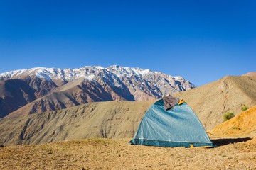 Igloo green camping tent on arid ground with splendid views of Andes snowy mountain range on the...