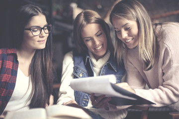 Cheerful young students girls at home learning together.