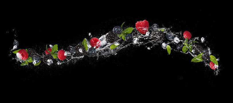 Fototapeta Mix of berry fruit in water splash, isolated on black background