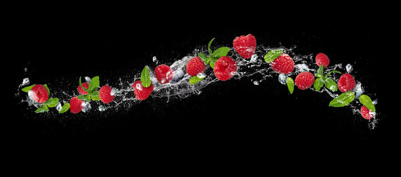 Fototapeta Raspberries falling in water splash on black background