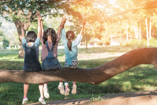 Children friendship concept with happy girl kids in the park having fun sitting under tree playing together enjoying good memory and moment of student friend lifestyle in school summer time day