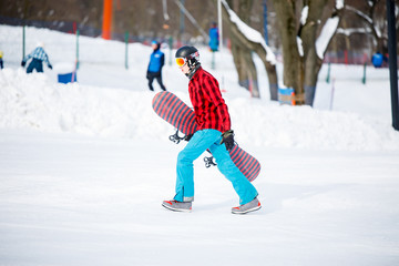 Photo of sporty man with snowboard walking on snowy resort