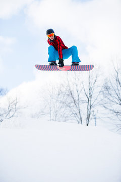 Photo of athlete with snowboard jumping in snowy resort