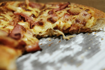 Close-up shot of tasty Italian pizza with ham, and onion in delivery box