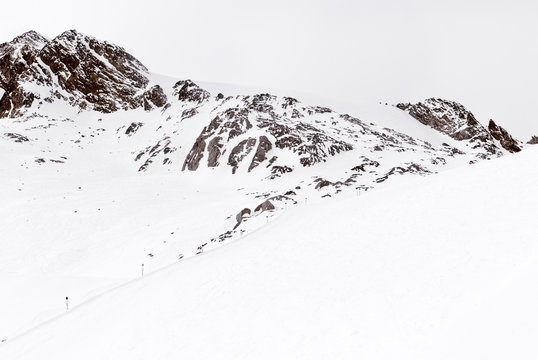 Minimalist mountain landscape. Ski trail and rock in the snow