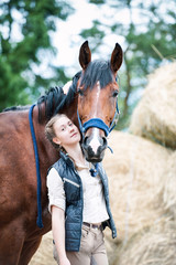 Fototapeta premium Young pretty teenage girl equestrian hugs her favorite horse
