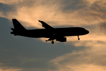 Fototapeta na wymiar Silhouette passenger airplane flying away in to sky high altitude on sunset
