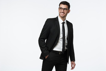 Young business man walking in studio, making step, wearing formal suit, isolated on grey background