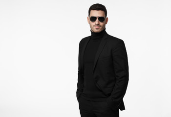 Serious body guard or secret agent wearing suit and sunglasses, isolated on grey background - obrazy, fototapety, plakaty