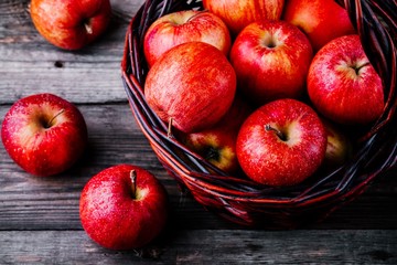 red ripe apples in a basket on a wooden background