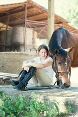 Young teenage girl equestrian sitting close to her favorite horse