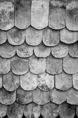 Close-up of old and weathered roof tiles texture background with vignette in black and white.