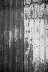 Close-up of a rusty and corrugated iron metal construction site wall texture background with vignette in black and white.