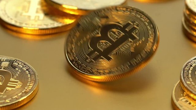 Coin golden bitcoin rotation, twist and falls on a golden background. Slow motion video 120 fps.