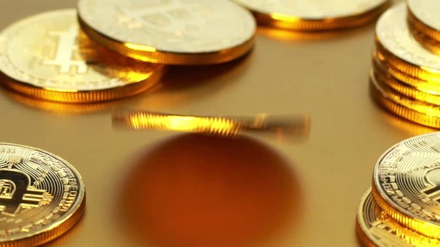 Coin golden bitcoin rotation, twist and falls on a golden background. Slow motion video 120 fps.