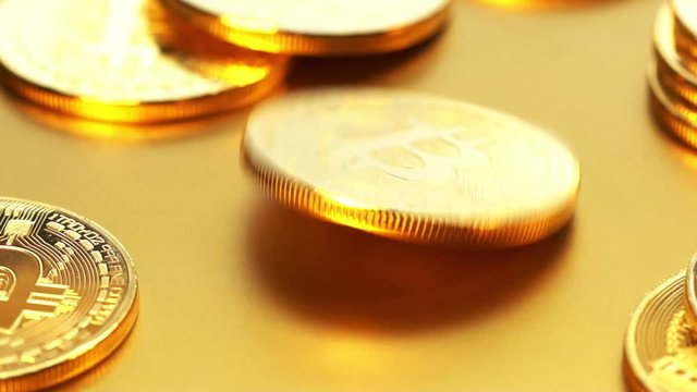 Coin golden bitcoin rotation, twist and falls on a golden background. Slow motion video 120 fps.
