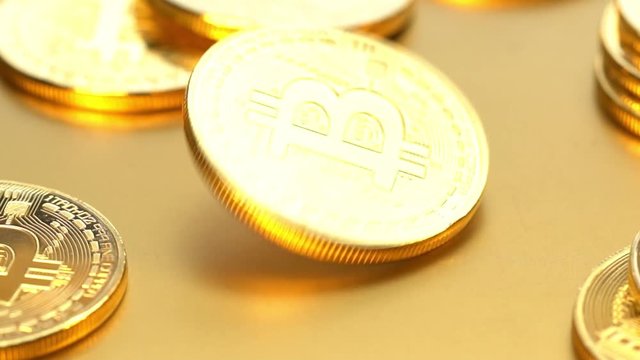 Coin golden bitcoin rotation, twist and falls on a golden background. Slow motion video 120 fps.